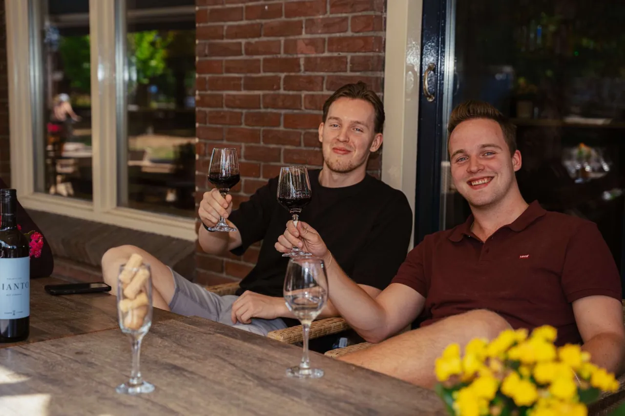 2 vrienden die proosten met rode wijn